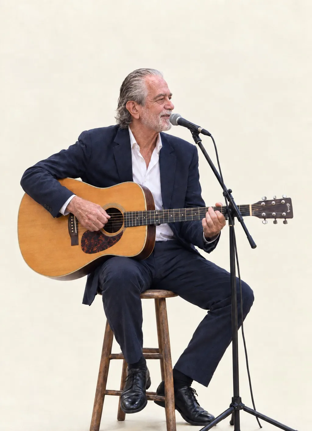 Kostas Pittadakis sitzt mit Gitarre am Mikrofon und singt